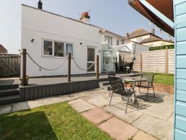 A backyard with a raised wooden deck and a patio area with metal chairs and a glass table at Pier View in Paighton