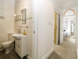 A small bathroom with a toilet and sink next to a hallway leading to a bedroom at Pier View in Paighton
