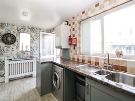 A kitchen with a washing machine under the counter a double sink and a fire extinguisher on the wall at Pier View in Paighton