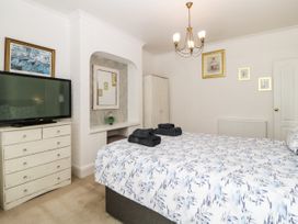 A bedroom with a bed with patterned bedding a chest of drawers with a tv a wardrobe and framed pictures on the wall at Pier View in Paighton