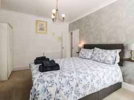 A bedroom with a double bed with patterned bedding black towels on the bed two bedside tables with lamps a wardrobe and framed pictures on the wall at Pier View in Paighton