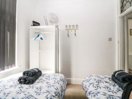 A bedroom with two single beds and folded towels on them a white wardrobe with hangers a fan and a window with blinds at Pier View in Paighton