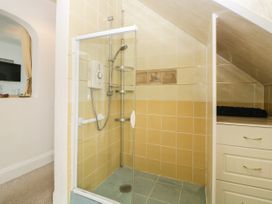 A tiled shower enclosure with a glass door and a white electric shower at Pier View in Paighton