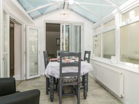 A dining area with a table set for tea and four chairs under a glass roof at Pier View in Paighton