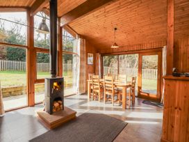 A dining room with a stove and wooden dining table at 26 Dukes Meadow Greystoke near Penrith