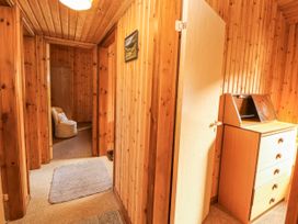 A hallway with doors and a chair at 26 Dukes Meadow in Greystoke near Penrith