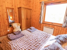 A bedroom with a bed, wardrobe, mirror, and chair at 26 Dukes Meadow in Greystoke near Penrith