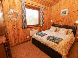 A bedroom with a bed and wooden walls at 26 Dukes Meadow in Greystoke near Penrith