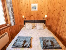 A bedroom with a bed and wooden walls at 26 Dukes Meadow Greystoke near Penrith