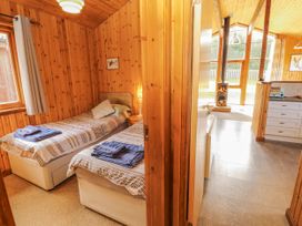 A bedroom with two beds and a view into the kitchen area at 26 Dukes Meadow in Greystoke near Penrith