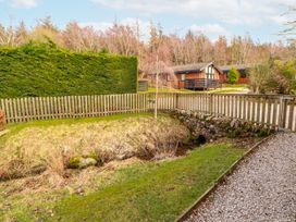 A garden with a fence, grass, and wooden cabins at 26 Dukes Meadow Greystoke near Penrith