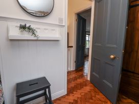 A hallway with a mirror and shelf at The Coach House in Prestatyn