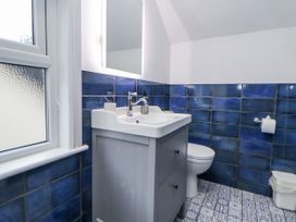A bathroom with a sink, toilet, and mirror at The Coach House in Prestatyn
