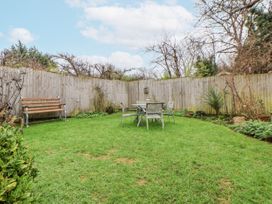 A garden with a table and chairs along with a bench at The Coach House in Prestatyn
