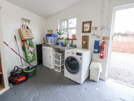 A laundry room with a washing machine and various cleaning supplies at The Coach House in Prestatyn