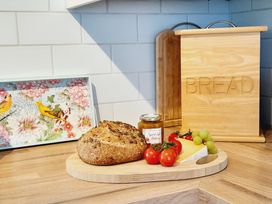 A kitchen with bread and cheese on a cutting board at Crab Cottage in Ilfracombe