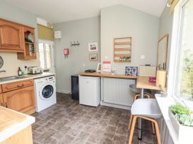 A kitchen with a washing machine and fridge at Doe Foot Cottage in Ingleton