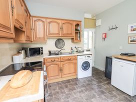 A kitchen with wooden cabinets and appliances at Doe Foot Cottage Ingleton