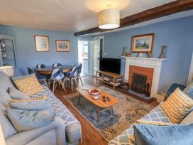 A living room with a sofa, dining table and television at Delphinium in Blakeney, Norfolk