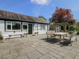 An outdoor patio area with wooden table and chairs outside a white house with black door at The Old Beams at Pont y Forwyn in Llansantffraidd-ym-Mechain near Welshpool