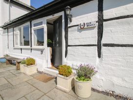 The exterior of a white brick building with black beams a black door partially open three potted plants a wooden bench and a sign reading The Old Beams at The Old Beams at Pont y Forwyn Llansantffraidd-ym-Mechain near Welshpool