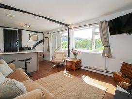 A living room with a sofa armchair coffee table flowers and a wall-mounted tv at The Old Beams at Pont y Forwyn Llansantffraidd-ym-Mechain near Welshpool