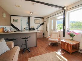 A room with stools by a countertop an armchair a wooden side table with flowers and large windows at The Old Beams at Pont y Forwyn Llansantffraidd-ym-Mechain near Welshpool