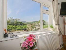 A window with a view of a garden and hills outside a room with a radiator flowers and a small plant at The Old Beams at Pont y Forwyn in Llansantffraidd-ym-Mechain near Welshpool