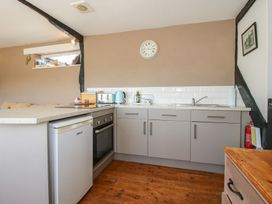 A kitchen with gray cabinets a countertop refrigerator oven and wooden floor at The Old Beams at Pont y Forwyn in Llansantffraidd-ym-Mechain near Welshpool