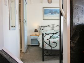 A bedroom with a black metal bed frame a blue nightstand with a lamp and a framed picture on the wall at The Old Beams at Pont y Forwyn in Llansantffraidd-ym-Mechain near Welshpool