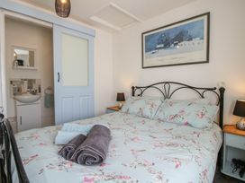 A bedroom with a bed with floral bedding and towels on it a bedside table with a lamp and a sliding door leading to a small bathroom at The Old Beams at Pont y Forwyn Llansantffraidd-ym-Mechain near Welshpool