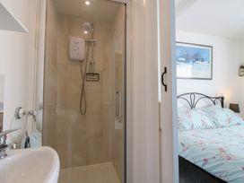 A bathroom with a shower and sink next to a bedroom with a bed and framed picture on the wall at The Old Beams at Pont y Forwyn in Llansantffraidd-ym-Mechain near Welshpool