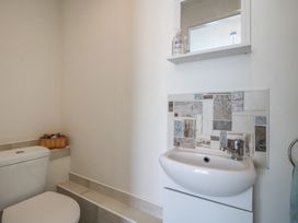 A small bathroom with a toilet sink mirror and tiled backsplash at The Old Beams at Pont y Forwyn in Llansantffraidd-ym-Mechain near Welshpool