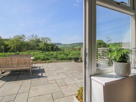 A patio with wooden benches and a table overlooking a grassy area and hills beyond at The Old Beams at Pont y Forwyn in Llansantffraidd-ym-Mechain near Welshpool