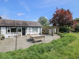 A white cottage with outdoor seating and a wooden pergola next to a grassy area at The Old Beams at Pont y Forwyn in Llansantffraidd-ym-Mechain near Welshpool