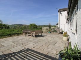 An outdoor patio area with wooden table and chairs and potted plants alongside a white house at The Old Beams at Pont y Forwyn Llansantffraidd-ym-Mechain near Welshpool