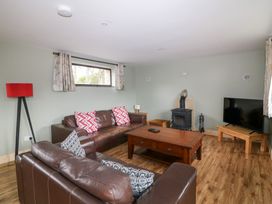 A living room with a sofa, coffee table, and television at The Owl's Hoot in Tacumshane, County Wexford