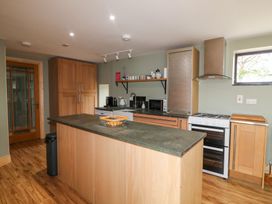 A kitchen with various appliances and wooden cabinetry at The Owl's Hoot in Tacumshane, County Wexford