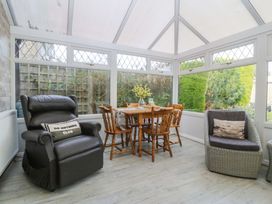 A conservatory with a dining table and chairs at The Cottage in Marian-Glas