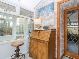 A conservatory with a wooden cabinet and a stool at The Cottage in Marian-Glas