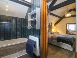 A bathroom with a bathtub and a view of a bedroom at The Cottage in Marian-Glas
