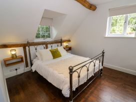 A bedroom with a metal bed and wooden beams at Lower Tundridge Cottage in Suckley near Malvern