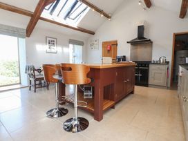 A kitchen with an island and bar stools at Wern Olau Cottage in Groeslon near Caernarfon