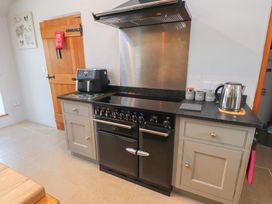 A kitchen with an oven, coffee maker, kettle and kitchen units at Wern Olau Cottage Groeslon near Caernarfon