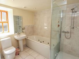 A bathroom with a sink, toilet, shower, and a bathtub at Wern Olau Cottage in Groeslon near Caernarfon