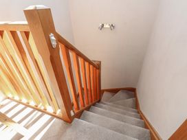 A staircase with wooden handrail and light fixture at Wern Olau Cottage Groeslon near Caernarfon