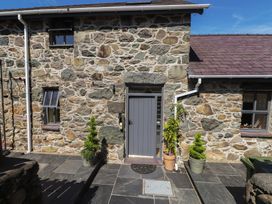 An outdoor area with stone wall, door, and planters at Wern Olau Cottage in Groeslon near Caernarfon
