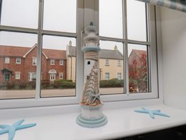 A lighthouse ornament on a windowsill with a view of houses at Coastal Cottage The Bay near Filey