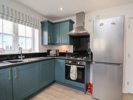 A kitchen with a sink, cooker, and fridge at Coastal Cottage The Bay near Filey