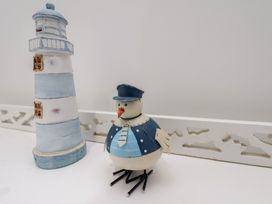 A lighthouse and a decorative bird on a shelf at Coastal Cottage The Bay near Filey